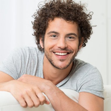 Portrait Of Happy Young Man Sitting On Sofa